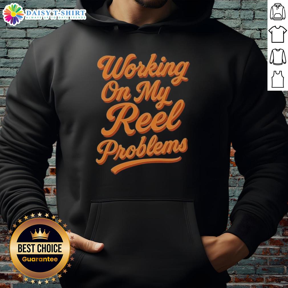 Person wearing an Awesome Working On My Reel Problems Fishing Hoodie while fishing by the lake, enjoying outdoor life.