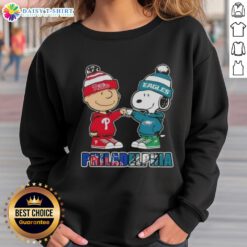 Adorable Charlie Brown and Snoopy fist bump in Philadelphia City Sports sweatshirt featuring Phillies and Eagles logos.
