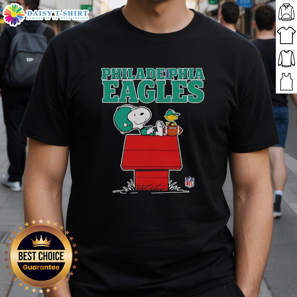Alt Text: Official Philadelphia Eagles Snoopy T-shirt featuring Peanuts style design with Snoopy chilling and holding a football.