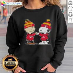 Charlie Brown and Snoopy fist bump in Kansas City Chiefs football sweatshirt, celebrating friendship and team spirit.