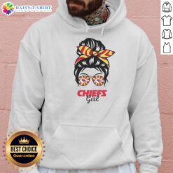 Cheerful Kansas City Chiefs girl in a messy bun, wearing glasses and a cozy hoodie, showing team spirit and style.