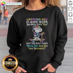 Funny Snoopy Growing Old Is Hard Work The Mind Says Yes But The Body Says What The Hell Are You Thinking Sweatshirt displayed on a hanger