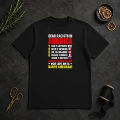 Official Dear Racists In America You Live On Is Native American t shirt in black, front view with clear bold white text